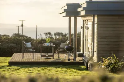 a woman sitting on a deck with a table and chairs at Stargazy in St. Agnes