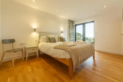 a bedroom with a large bed and a large window at Teyr Mor Cliff in St. Agnes