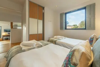 two beds in a room with a window at The Deck House in St. Agnes