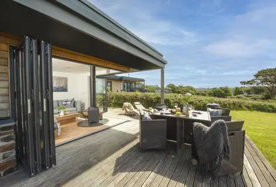 a patio with a table and chairs on a deck at The Deck House in St. Agnes