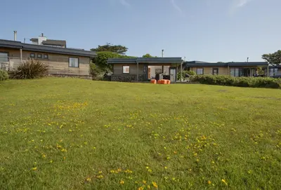 a yard with a house and a field of flowers at The Deck House in St. Agnes