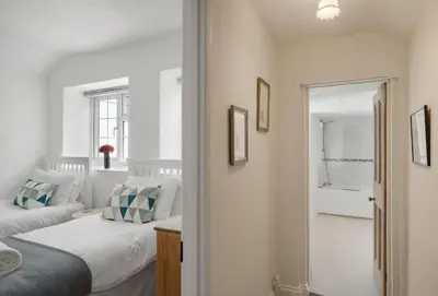 a bedroom with two beds and a bathroom with a tub at The Boy's Cottage in Portreath
