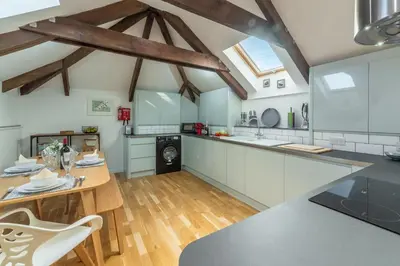a kitchen with white cabinets and a wooden table at The Shires in St. Agnes