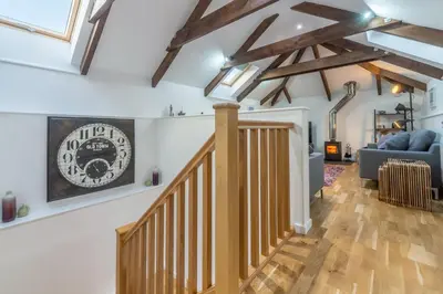a living room with a staircase and a clock on the wall at The Shires in St. Agnes