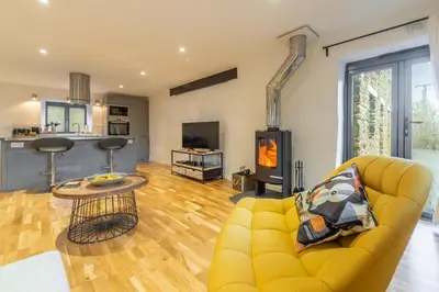 a living room with a yellow couch and a fireplace at The Stables in St. Agnes