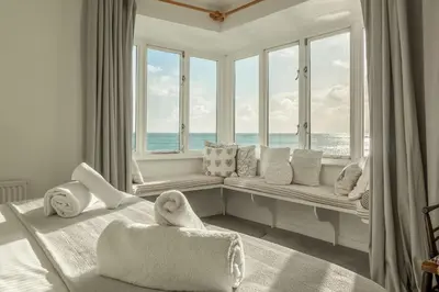 a bedroom with a window seat with a view of the ocean at The Watch House in Helston
