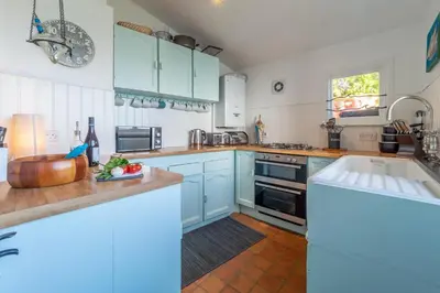 a kitchen with blue cabinets and a sink at The Watch House in Helston