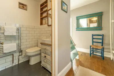 a bathroom with a toilet and a sink and a mirror at The Watch House in Helston