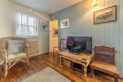 a living room with a television and a table and a chair at The Watch House in Helston