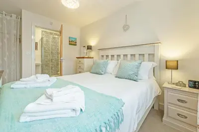 a bedroom with a large white bed with towels on it at The Seahouse in Portreath