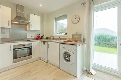 a kitchen with a washer and dryer next to a window at The Seahouse in Portreath