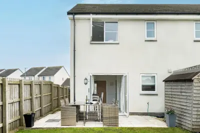 a white house with a table and a fence at The Seahouse in Portreath