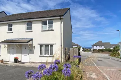 a white house on a street with purple flowers at The Seahouse in Portreath