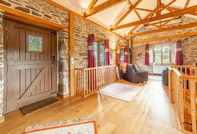a living room with a door and a brick wall at The Threshing Barn in Gwennap