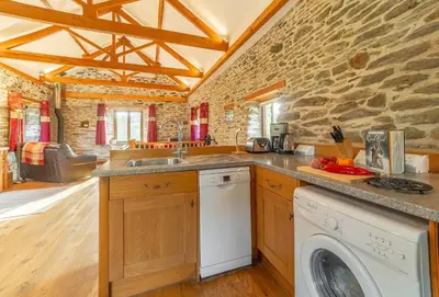 a kitchen with a washer and a stone wall at The Threshing Barn in Gwennap