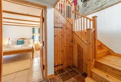 a hallway with a wooden staircase in a house at The Threshing Barn in Gwennap