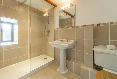 a bathroom with a sink and a shower and a toilet at The Threshing Barn in Gwennap