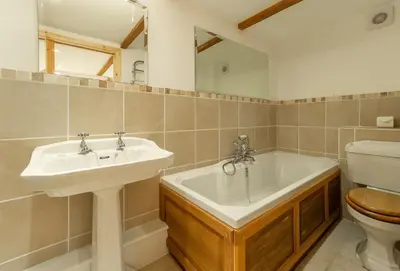 a bathroom with a sink and a tub and a toilet at The Threshing Barn in Gwennap