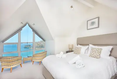 two beds in a room with a large window at Westaway in Portreath
