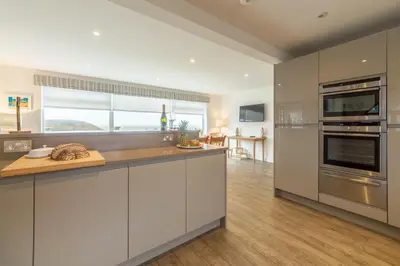 a kitchen with white cabinets and stainless steel appliances at Westerley in Portreath