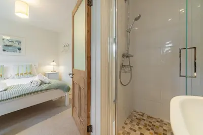 a bathroom with a shower and a bed and a sink at Westerley in Portreath