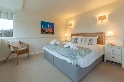 a bedroom with a bed and a chair and a window at Westerley in Portreath