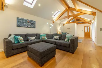 a living room with a gray couch and wooden floors at Westerley in Portreath