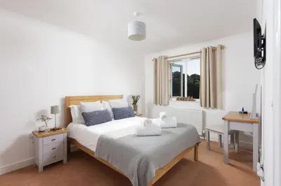 a white bedroom with a bed and a window at Waterfront House in Saint Clement