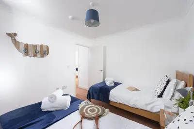 two beds in a bedroom with white walls at Waterfront House in Saint Clement