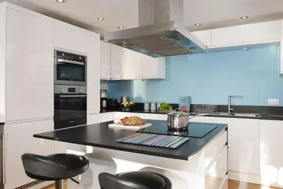a kitchen with white cabinets and a black counter top at Wavelength in St. Agnes