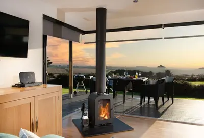 a wood stove in a living room with a table at Wavelength in St. Agnes