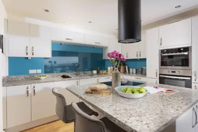 a kitchen with white cabinets and a counter with a bowl of fruit at Triskel in St. Agnes