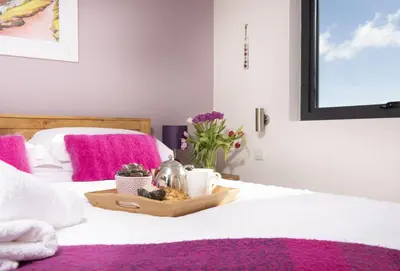 a bed with a tray of food and flowers on it at Triskel in St. Agnes