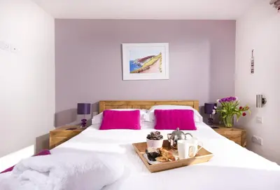 a bedroom with two beds with white sheets and pink pillows at Triskel in St. Agnes