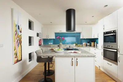 a kitchen with white cabinets and blue walls at Triskel in St. Agnes