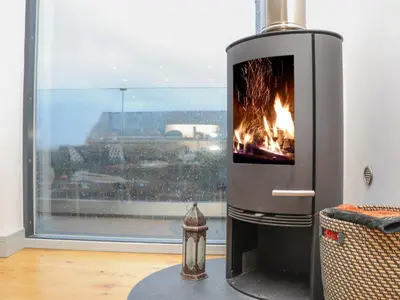 a fireplace in a living room with a fire at Idlewild, 2 Wheal Turnavore in St. Agnes