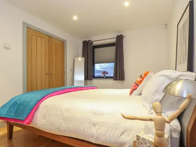 a bedroom with a bed with a lamp and a window at Idlewild, 2 Wheal Turnavore in St. Agnes