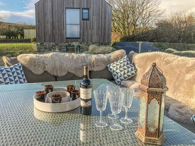 a table with a bottle of wine and wine glasses at Idlewild, 2 Wheal Turnavore in St. Agnes