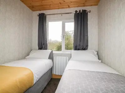two beds in a small room with a window at Lodge Two in Truro