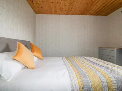 a bedroom with a white bed with orange pillows at Lodge Two in Truro