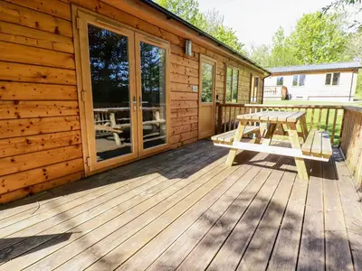 a wooden cabin with a picnic table on the deck at Lodge Three in Truro