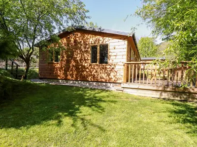 a log cabin in a yard with a grass field at Lodge Three in Truro