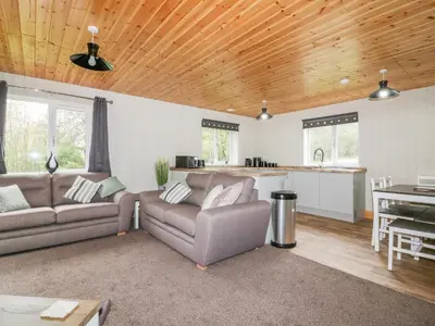 a living room with two couches and a kitchen at Lodge Three in Truro
