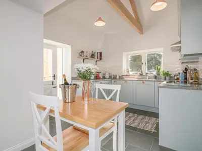 a kitchen with a wooden table with flowers on it at The Bull Pen in St Austell