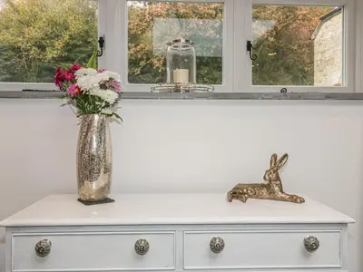 a vase of flowers on a dresser with a window at The Bull Pen in St Austell