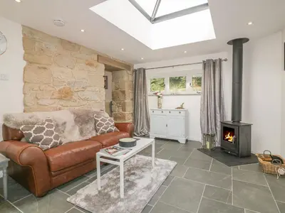 a living room with a leather couch and a wood stove at The Bull Pen in St Austell
