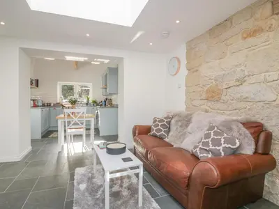 a living room with a leather couch and a stone wall at The Bull Pen in St Austell