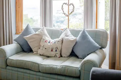 a blue couch with pillows on it in front of a window at Wisteria in St Austell