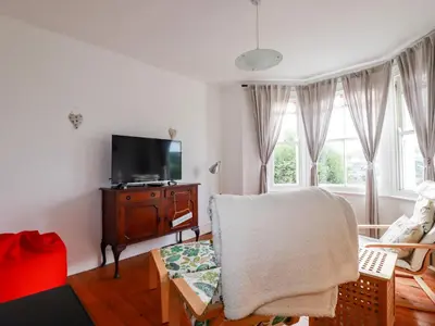 a living room with a tv and a chair at Wisteria in St Austell
