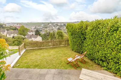 a bench sitting in a yard next to a hedge at Wisteria in St Austell